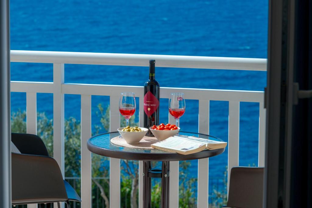 una mesa con 2 copas de vino en el balcón en Apartments Lea, en Cavtat