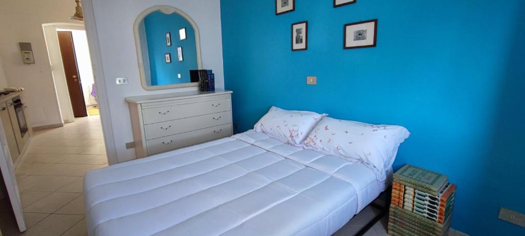 1 dormitorio con cama blanca y pared azul en BiblioSosta anche al 1° Piano anno 2024, en Ventimiglia