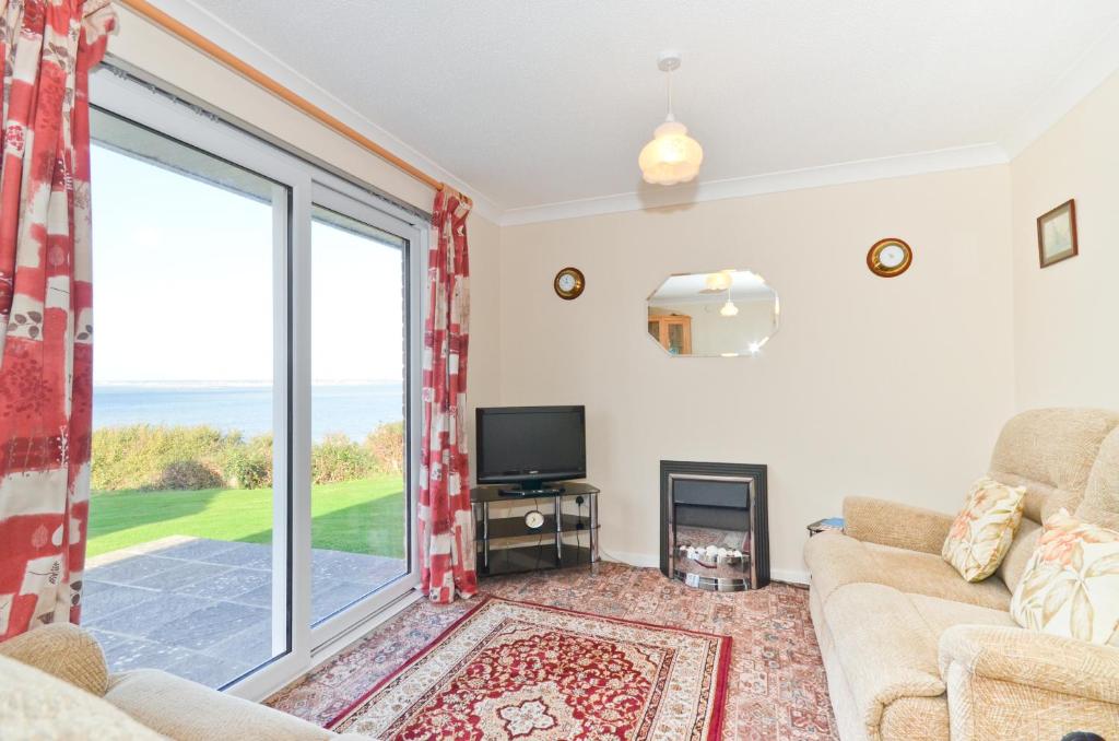 a living room with a couch and a large window at 2 Brambles Farm Holiday Bungalow in Freshwater