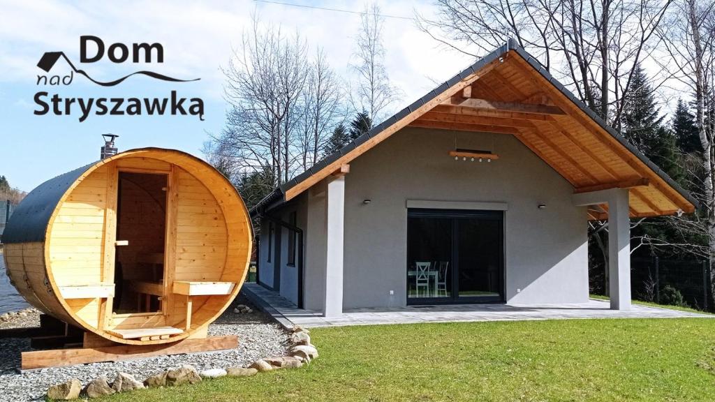 a small wooden house with a large door in front of it at Dom nad Stryszawką z SAUNĄ - domek wypoczynkowy in Stryszawa