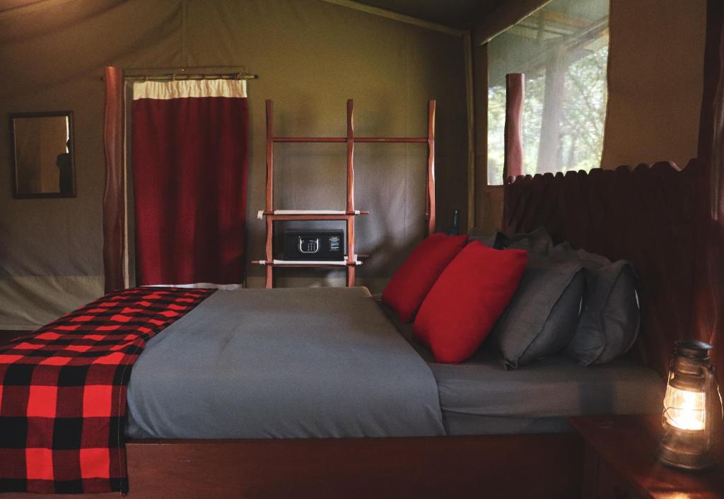 ein Schlafzimmer mit einem großen Bett mit roten Kissen in der Unterkunft Drunken Elephant Mara in Sekenani