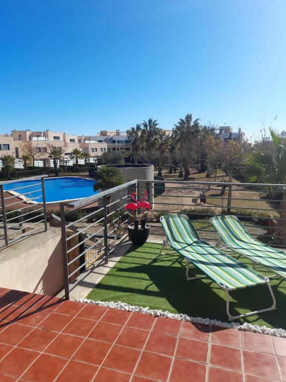 um pátio com 2 espreguiçadeiras e uma piscina em Piso de lujo - descansar y trabajar en Golf Panoramica para 4 pers - internet fibra GRATIS em Sant Jordi