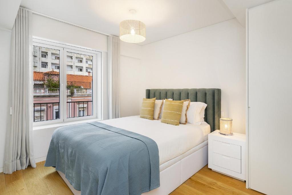- une chambre blanche avec un lit et une fenêtre dans l'établissement WHome Urban Oasis: Modern Living with Parking & AC, à Lisbonne