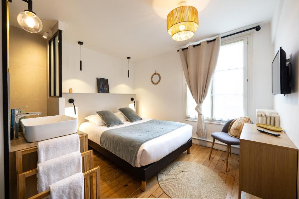 a bedroom with a bed and a sink and a window at Hotel de La Paix in La Rochelle