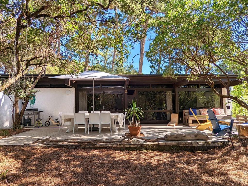 une maison avec un patio avec une table et des chaises dans l'établissement Villa spacieuse à 6 minutes des plages et marché, idéale pour familles et amis, WiFi inclus - FR-1-736-35, à Lège-Cap-Ferret