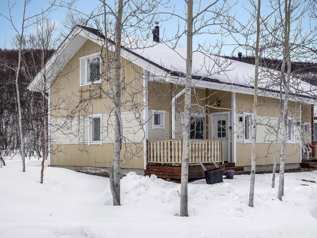 a house covered in snow with trees in the foreground at Holiday Home Lomahuoneisto b by Interhome in Utsjoki
