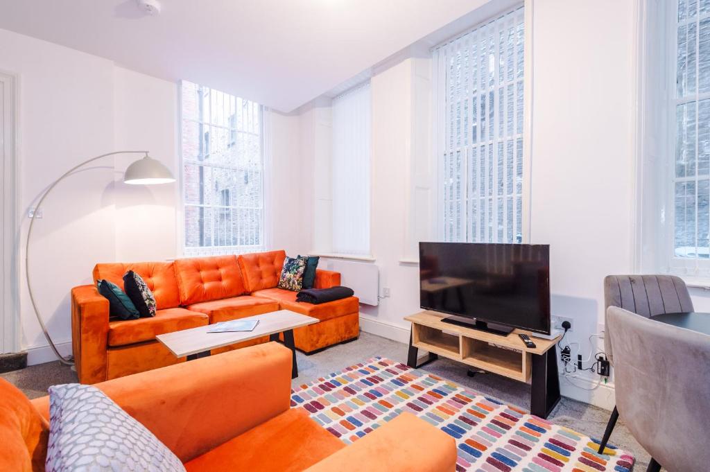 a living room with orange furniture and a flat screen tv at The Old Embassy by Guestz in Hull