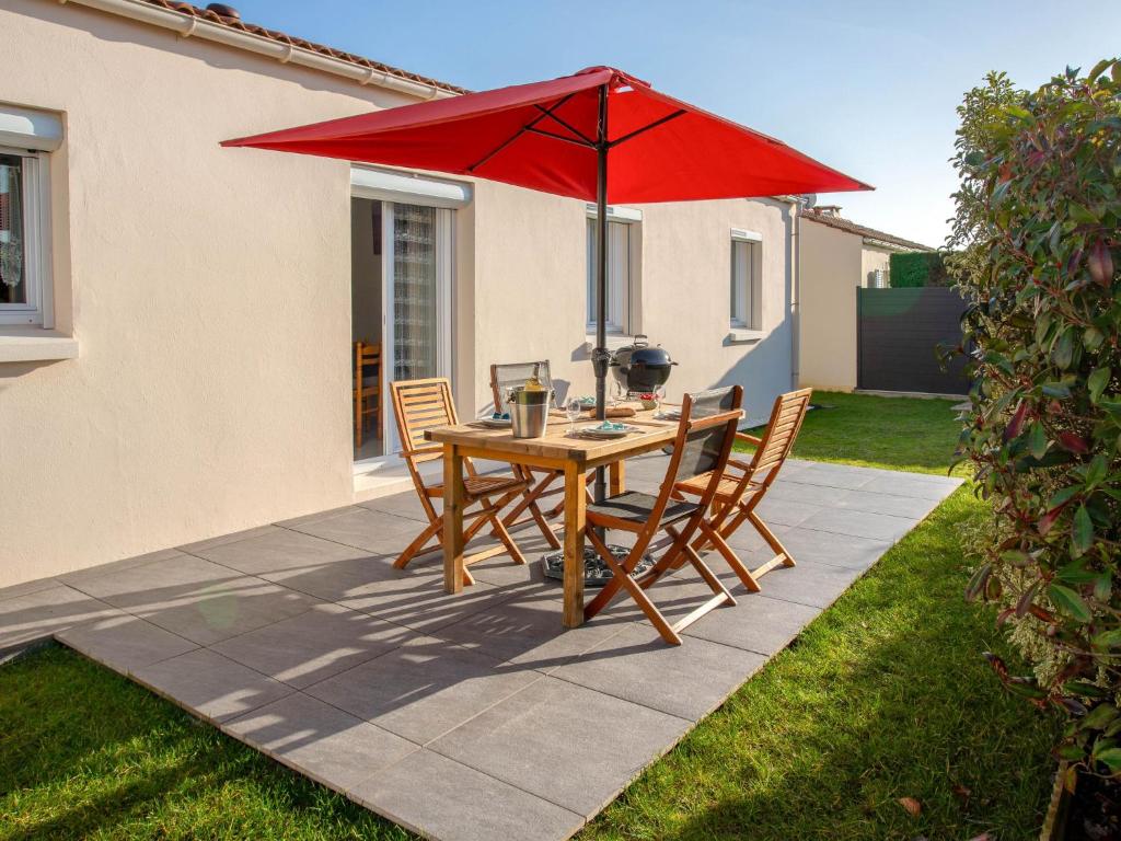 une table en bois avec des chaises et un parapluie rouge dans l'établissement Holiday Home Les Pêcheries by Interhome, à Pornic