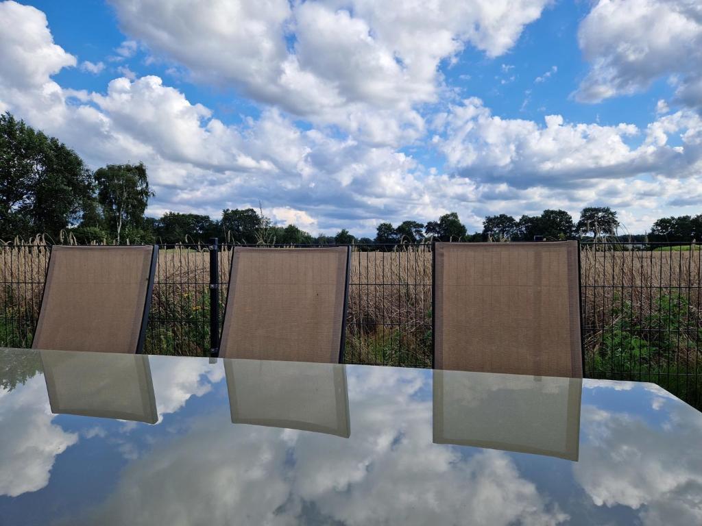 een reflectie van een hek en een hemel met wolken bij Haus Riehe - b50841 in Haselünne