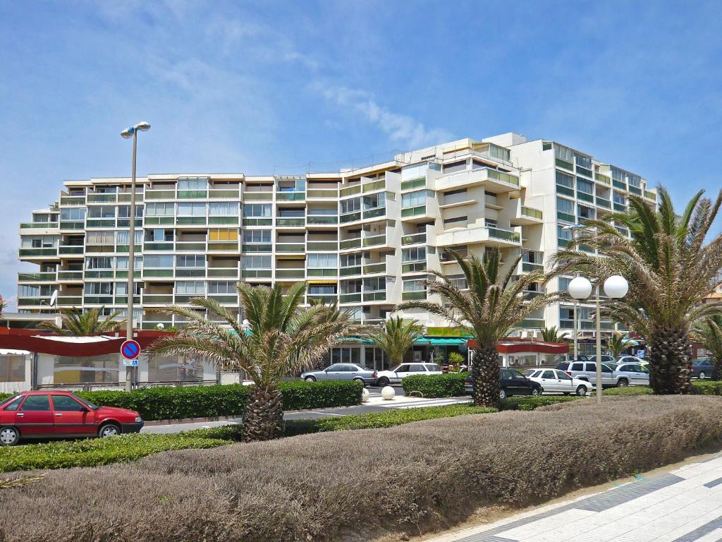 un grand bâtiment avec des palmiers dans un parking dans l'établissement Apartment Les Jardins de la Plage-12 by Interhome, à Canet