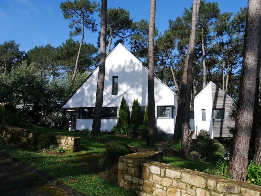 uma casa branca com árvores e uma parede de pedra em La Villa sous Les Pins em La Trinité-sur-Mer