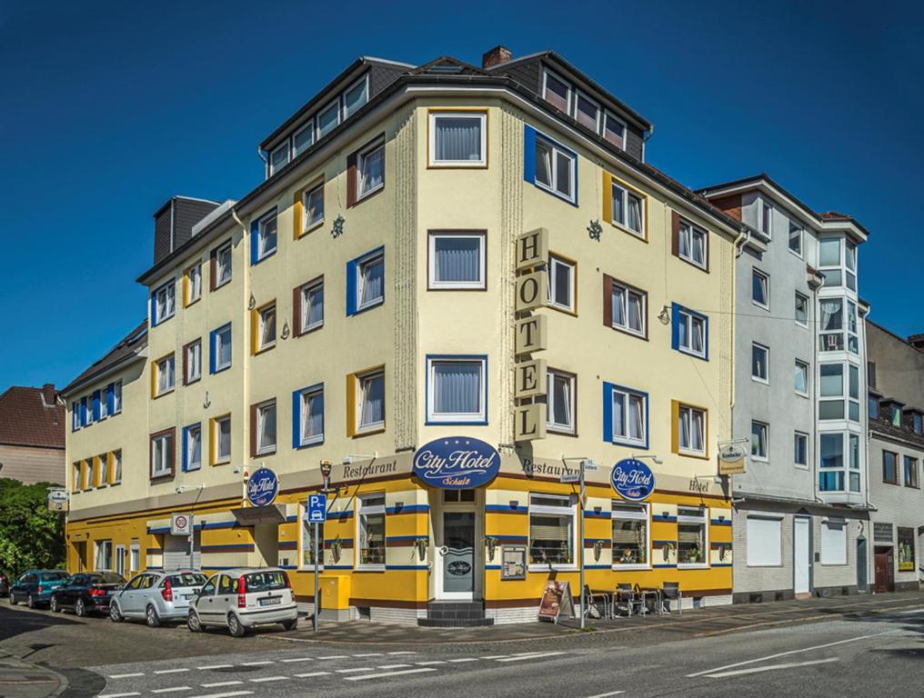 un grand bâtiment jaune avec des voitures garées devant lui dans l'établissement City Hotel, à Bremerhaven