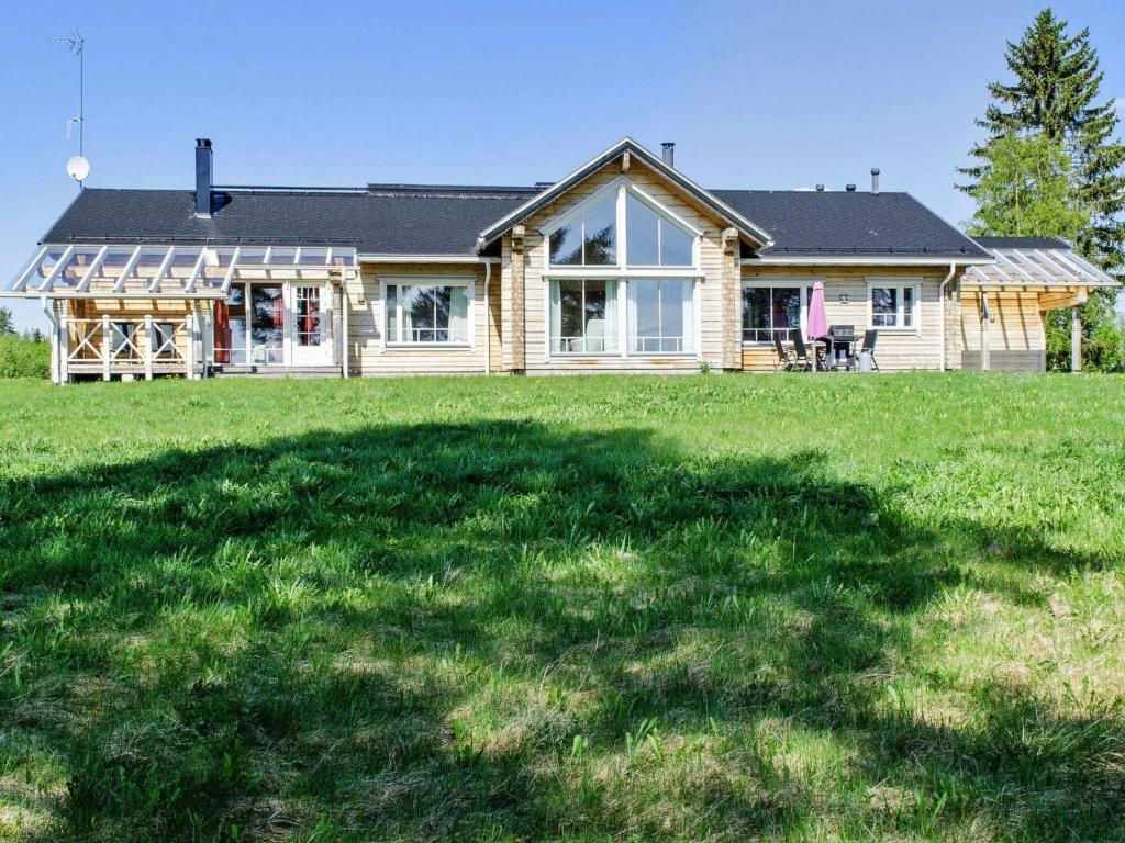 a house with a large grass field in front of it at Holiday Home Wooden ecovilla by Interhome in Haapalahti