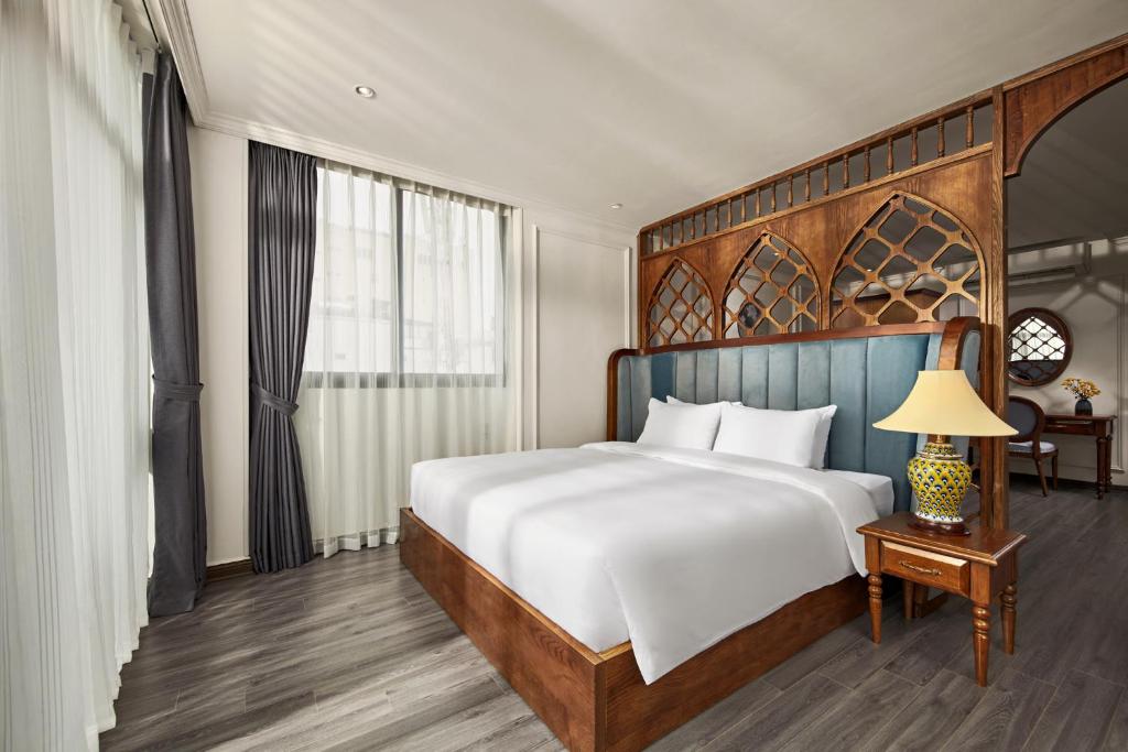 um quarto com uma cama grande e uma mesa com um candeeiro em Eliana Premio Hotel Hanoi em Hanói