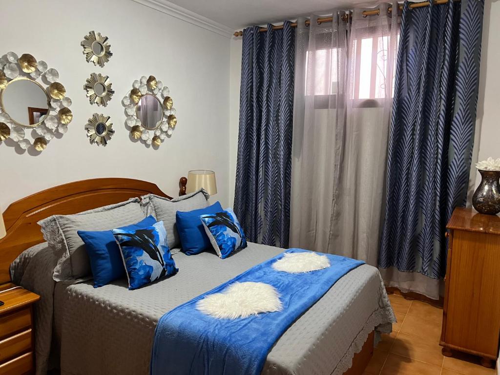 a bedroom with a bed with blue pillows and a window at La casita de la piscina in Adeje