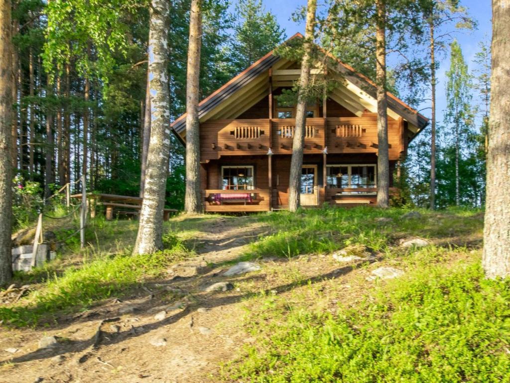 una cabaña de madera en el bosque con un camino delante en Holiday Home Utras by Interhome, en Punkaharju