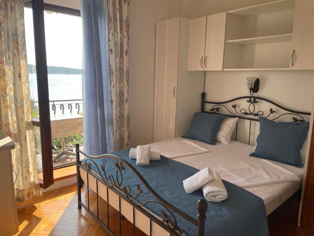 sypialnia z łóżkiem i dużym oknem w obiekcie Apartments Vila Miranda w mieście Barbat na Rabu