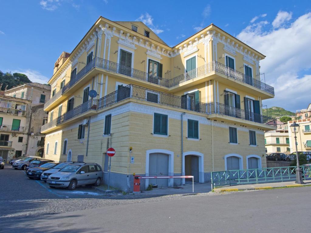 un grand bâtiment jaune avec des voitures garées devant lui dans l'établissement Apartment Mimì by Interhome, à Vietri