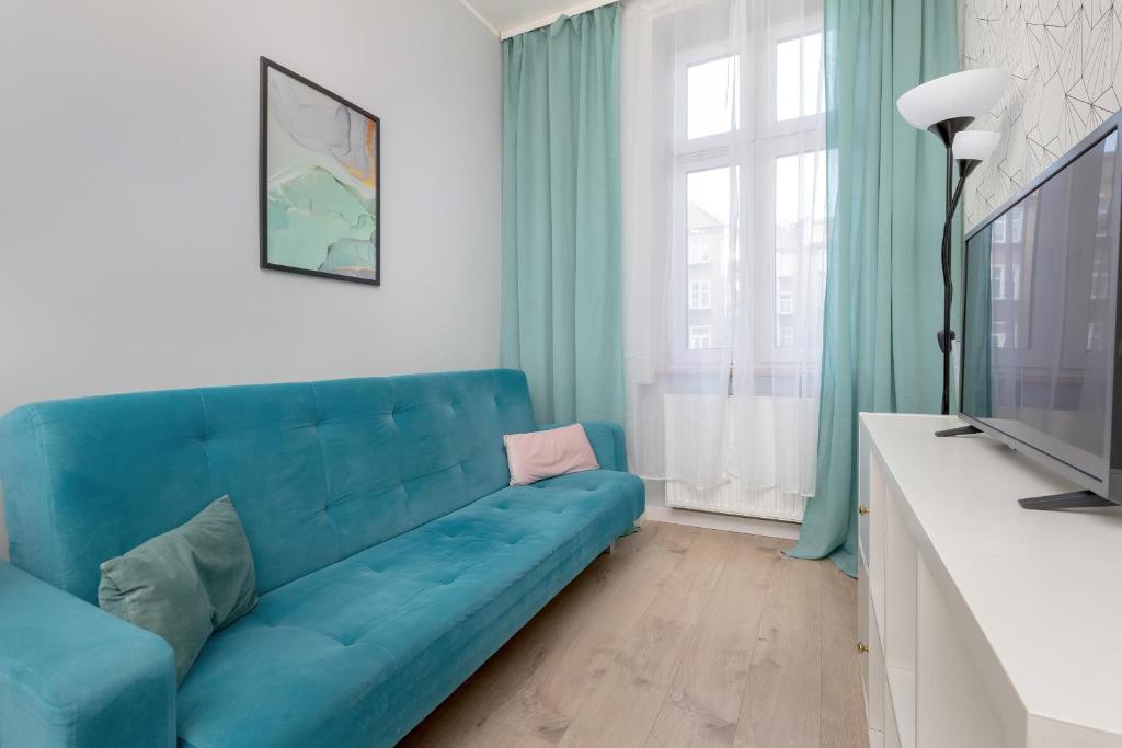 um sofá azul numa sala de estar com televisão em Cosy Studios near the Old Town in Gdańsk by Renters em Gdansk