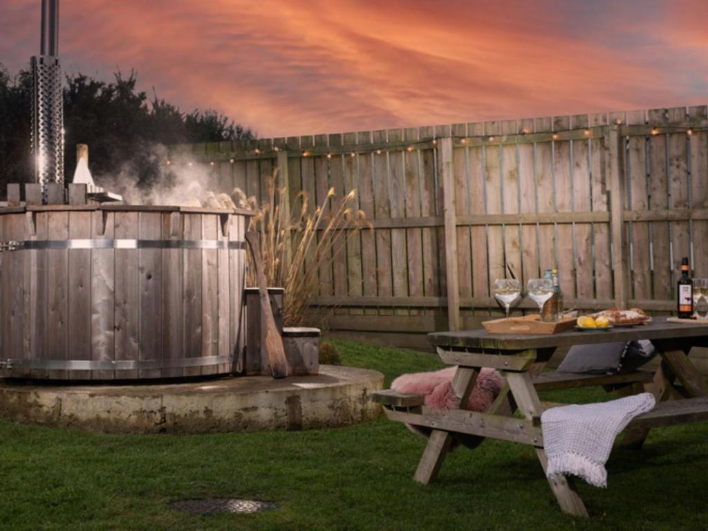 a picnic table and a grill with wine glasses at Chalet Wheal Prosper Hot Tub Lodge by Interhome in Helston