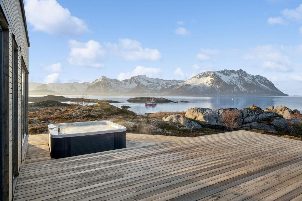 a bench on a wooden deck with mountains in the background at Fjordview Arctic Lodge with sauna and Jacuzzi in Lyngværet