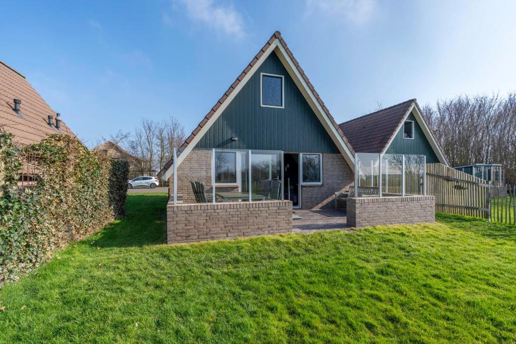 una casa con techo verde y patio en Nieuwlanderweg 75, en De Waal
