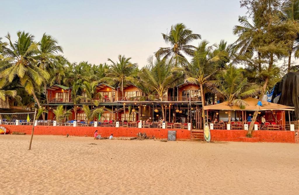 a resort on the beach with palm trees at Jardim a Mar in Agonda