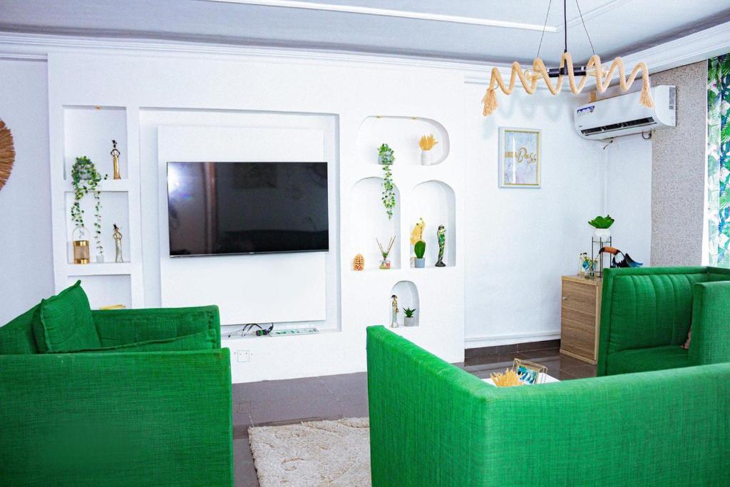 uma sala de estar com cadeiras verdes e uma televisão de ecrã plano em appartement cosy moon bonapriso em Douala