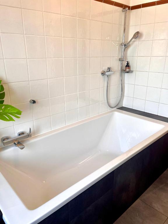 a white bath tub with a shower in a bathroom at LUXUS sApartments in der Kunstvilla &amp; kostenloses parken in Premstätten