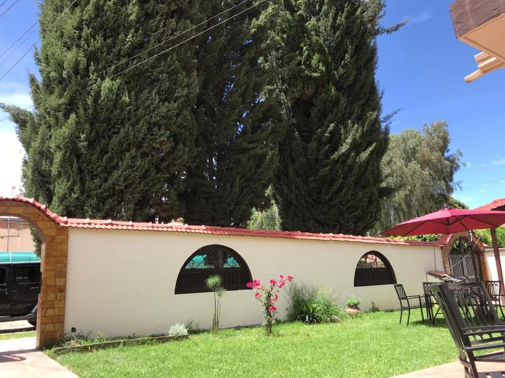 een achtertuin met een tafel, stoelen en bomen bij La Casa de Los Pinos in Cochabamba