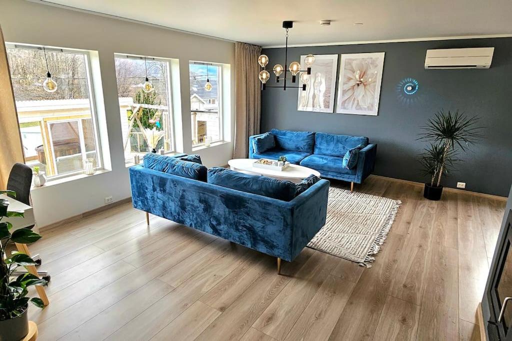 ein Wohnzimmer mit einem blauen Sofa und 2 Stühlen in der Unterkunft Familie bolig med hage in Lyngdal