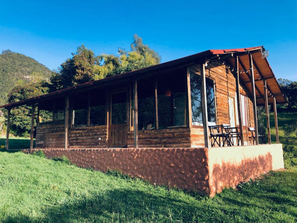 una cabaña de madera en un campo de césped con árboles en el fondo en Refugio Aventura, espectacular cabaña en las montañas de Tabio, Cundinamarca, en Tabio