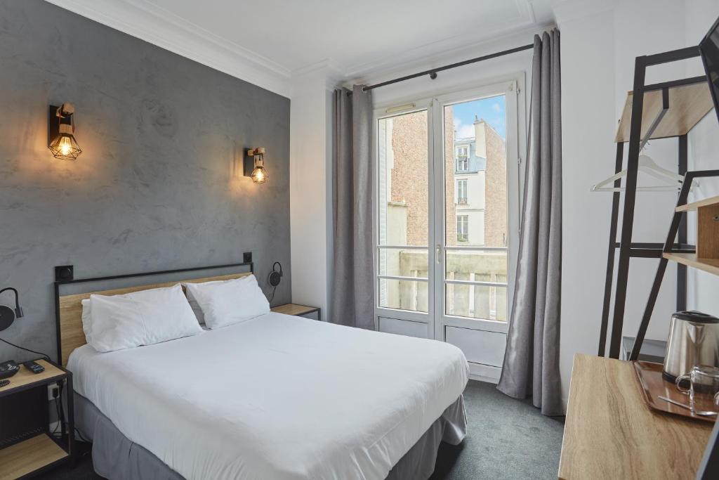 a bedroom with a bed and a large window at Hotel Auguste in Paris