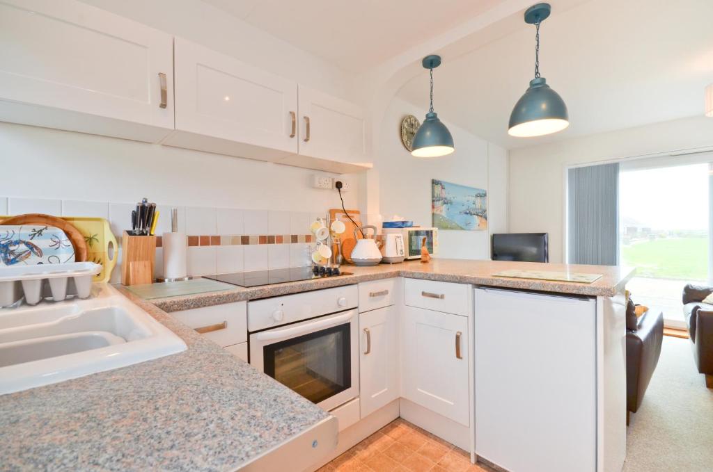 a kitchen with white cabinets and a counter top at The Hideaway, 65 Salterns Beach Bungalows, Seaview in Seaview