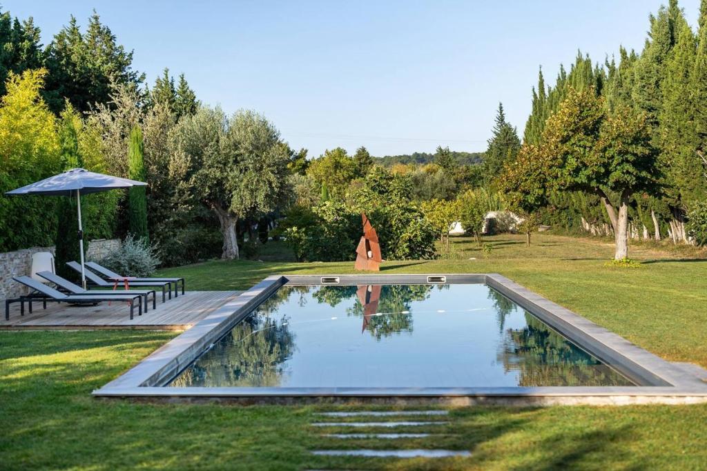 a swimming pool in a yard with a bench and an umbrella at Maison de 4 chambres avec piscine privee jacuzzi et terrasse a Noves in Noves