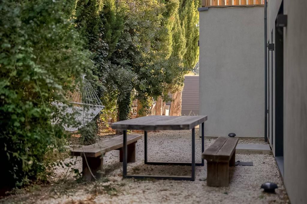 a picnic table and two benches in a yard at Maison de 4 chambres avec piscine privee jacuzzi et terrasse a Noves in Noves