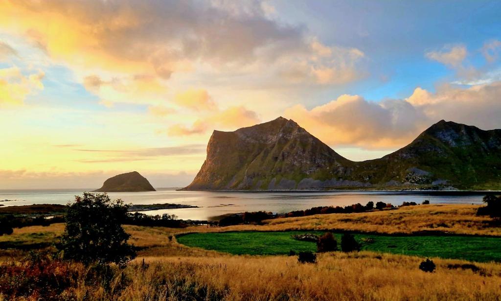 a sunset over a field with mountains and a body of water at Haukland Panorama in Offersøya