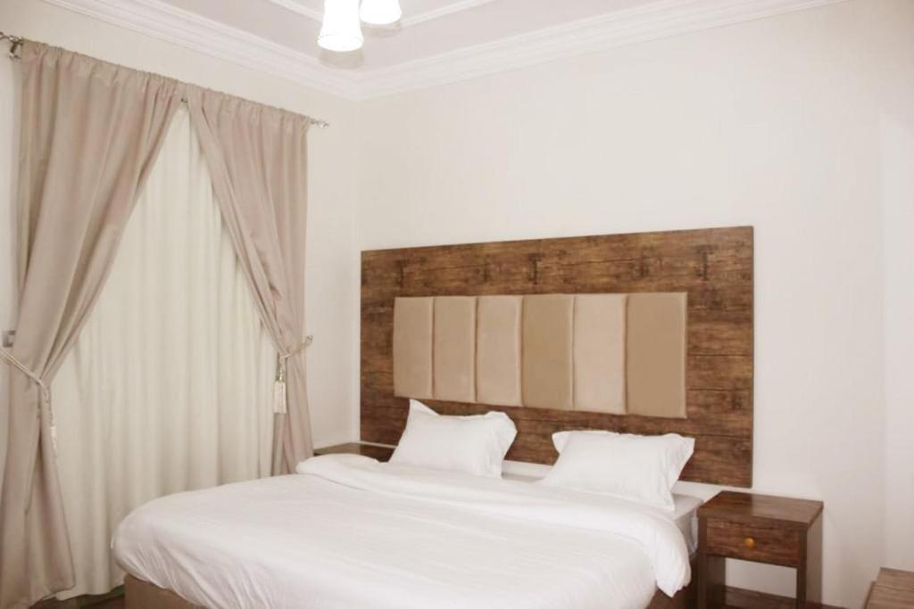 a bedroom with a large bed with white sheets at كيان العزيزية للشقق المخدومة - Kayan Al-Azizia Serviced Apartments in Jeddah