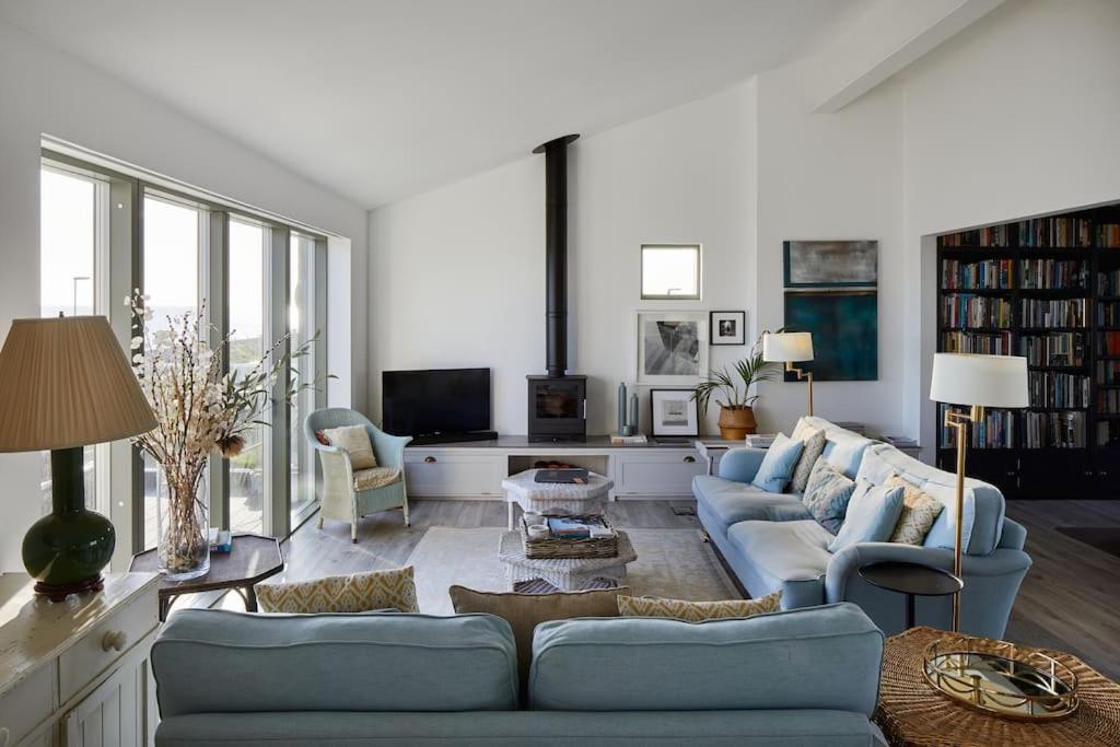 a living room with two blue couches and a tv at Stunning architect designed beachfront property in Selsey