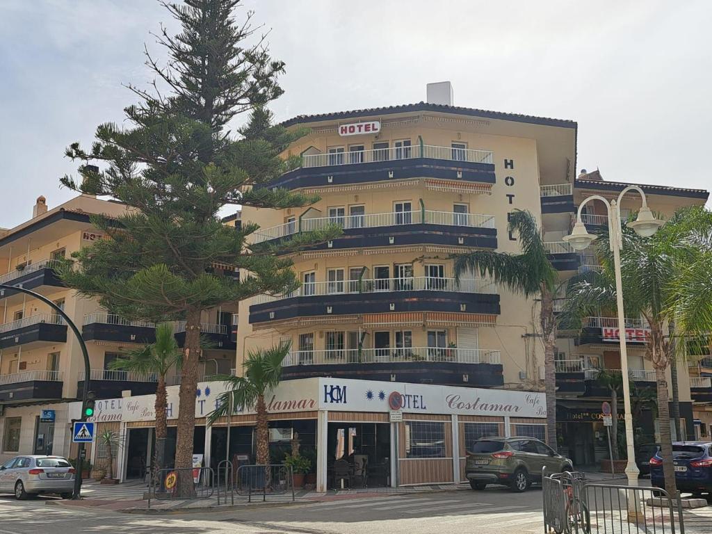 un gran edificio con un árbol delante en Hotel Costamar, en Morche