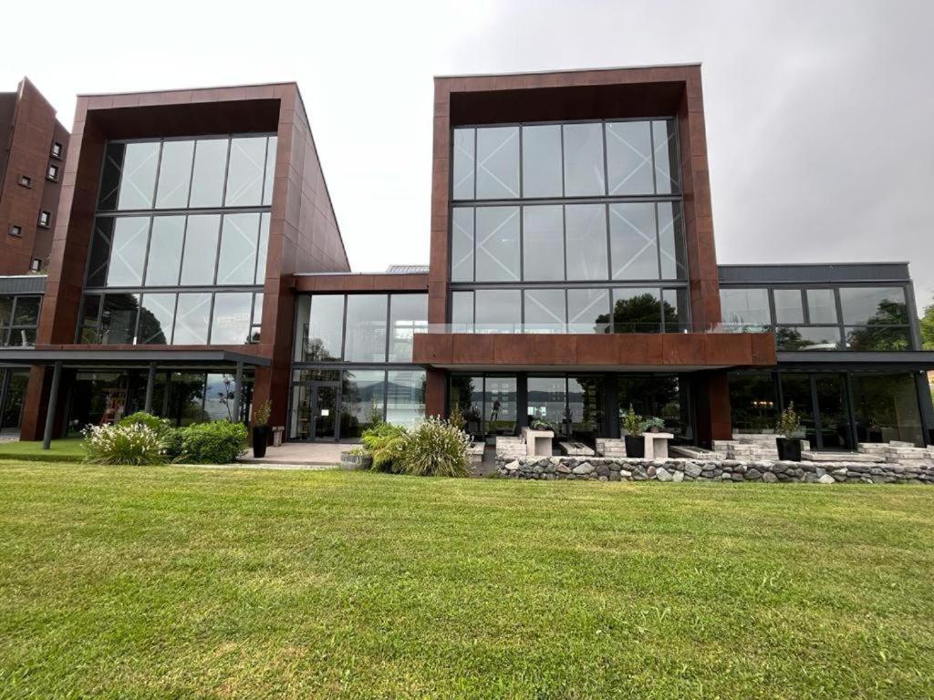 a large building with a grass field in front of it at Departamento Nuevo en Condominio La Puntilla Villarrica in Pucón