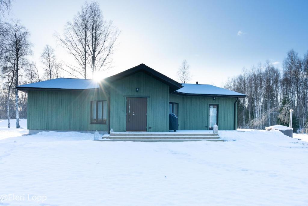 een groen huis met sneeuw ervoor bij Paunküla Nature Resort in Kose