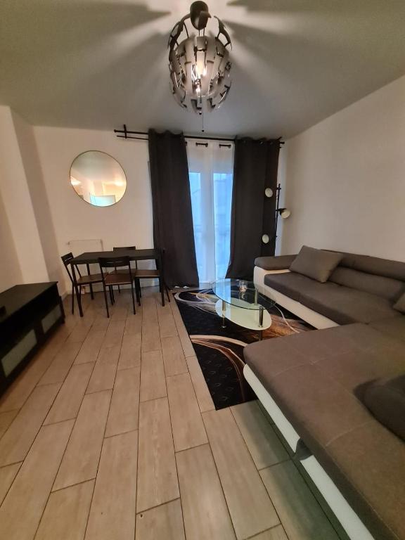 een woonkamer met een bank en een tafel bij Apt cosy village olympique in Saint-Ouen