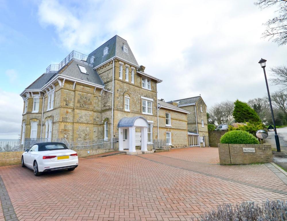 a white car parked in front of a large building at Stunning Ocean Views, The Priory in Shanklin
