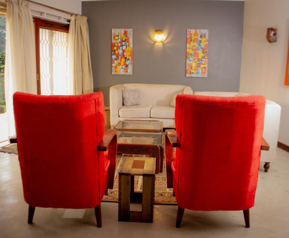 a living room with two red chairs and a couch at Spacious Residence with Garden Close to Acacia Mall Kololo in Kampala