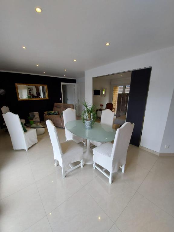 une salle à manger avec une table et des chaises blanches dans l'établissement Les Suites de Véronique, chez Véronique Olive, à Saint-Pair-sur-Mer