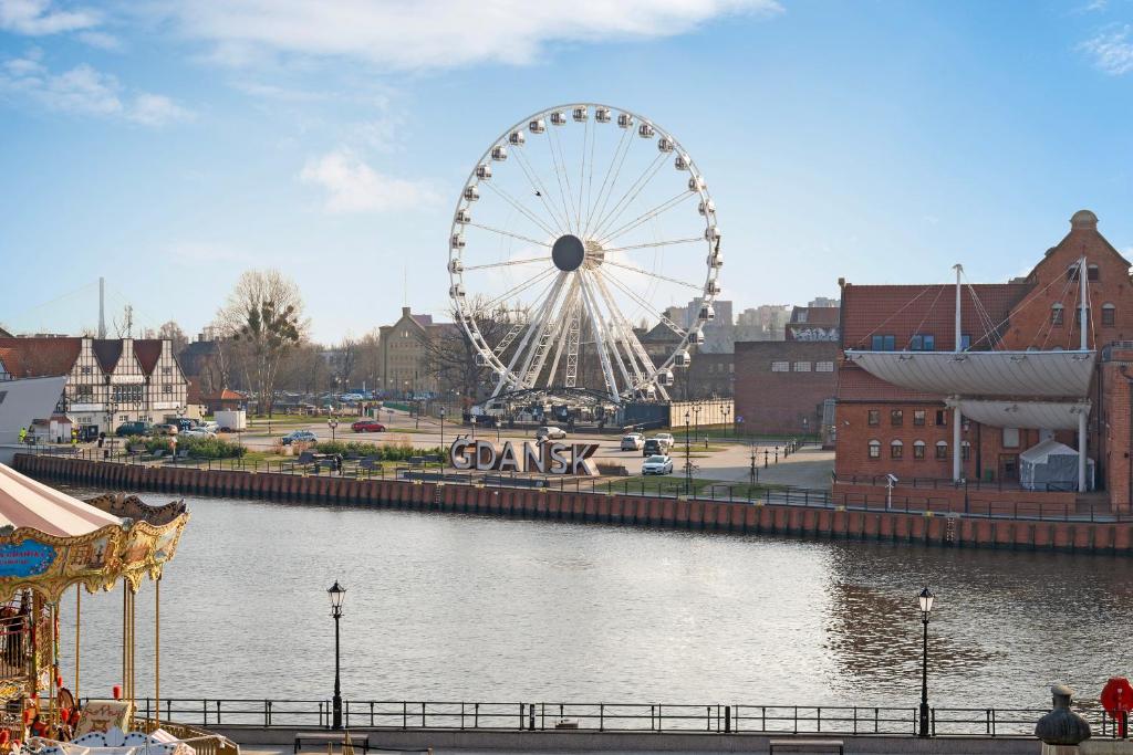 una noria en una ciudad junto a un río en Dom & House - Apartments Old Town Targ Rybny, en Gdansk