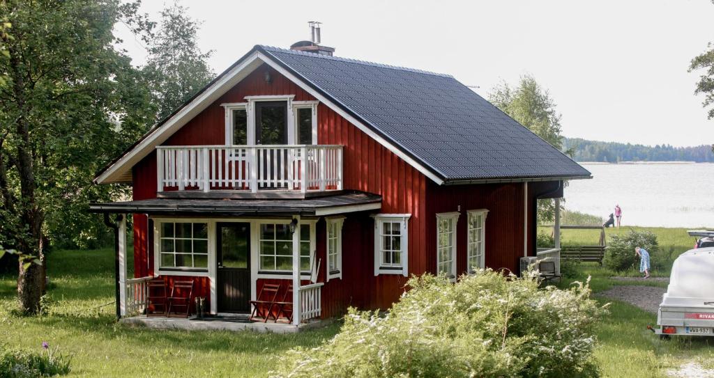 uma casa vermelha com um alpendre e uma varanda em Strömman mökki rannalla autotien päässä. 