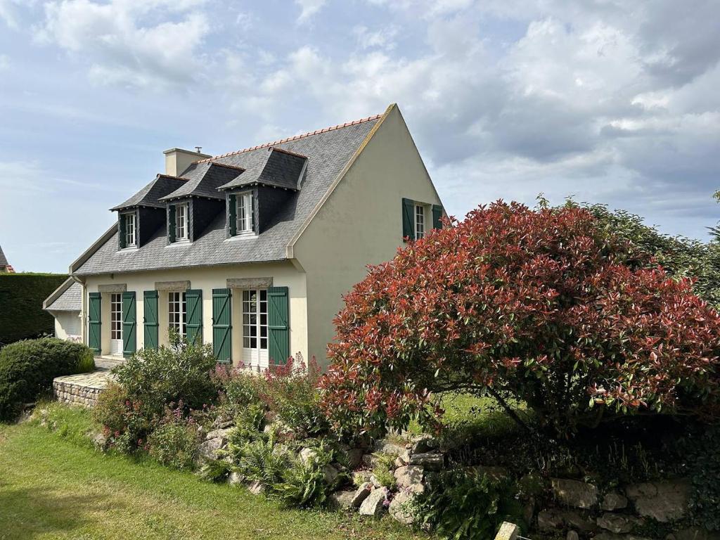 een wit huis met ramen en een bloeiende bush bij 611 - Maison 9 couchages, proche du Cap d'Erquy in Erquy