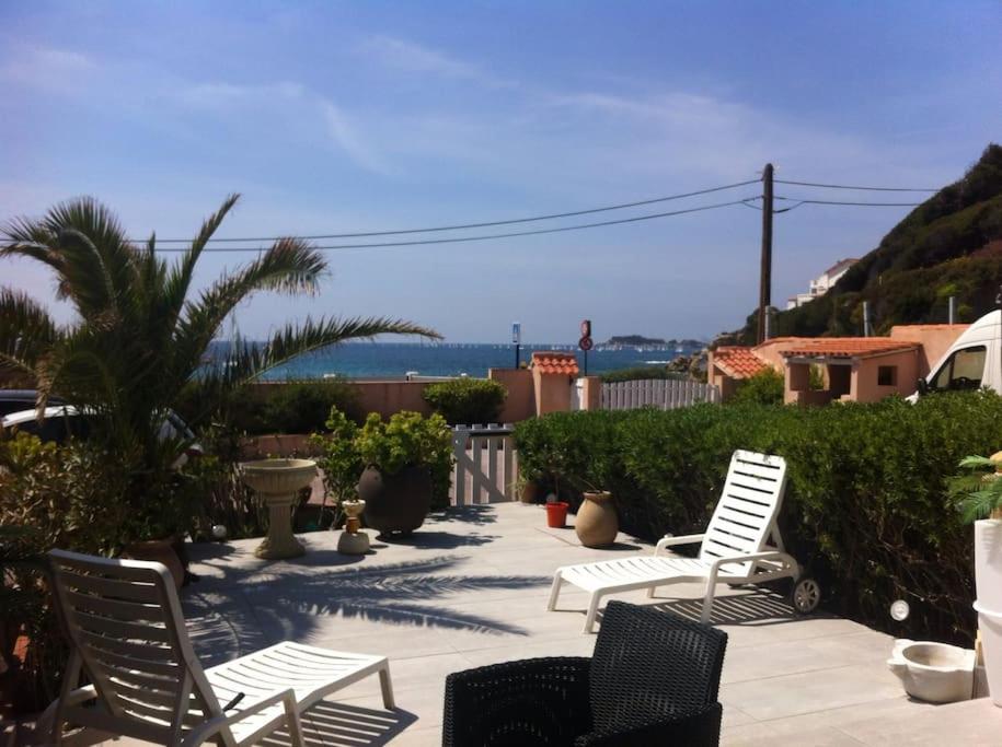 une terrasse avec 2 chaises et un palmier dans l'établissement Magnifique appartement face à la plage de Beaucours, à Sanary-sur-Mer
